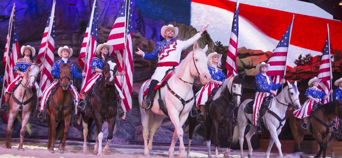 Dolly Parton's Stampede arena finale with riders carrying flags